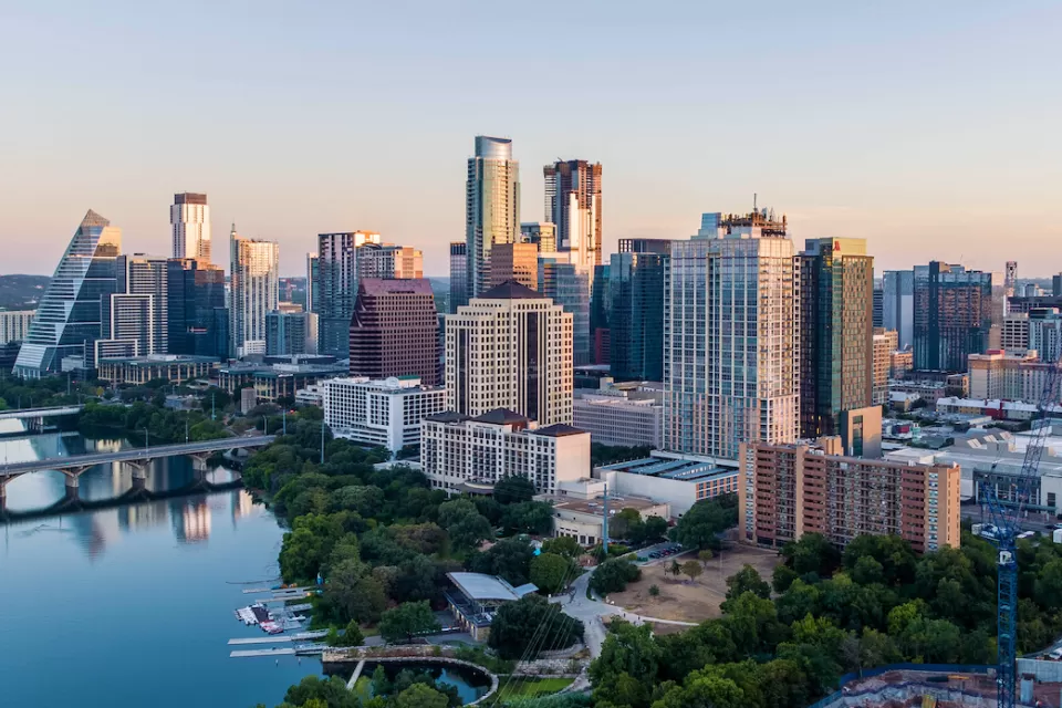View of Austin, Texas skyline with river in foreground during morning golden hour.